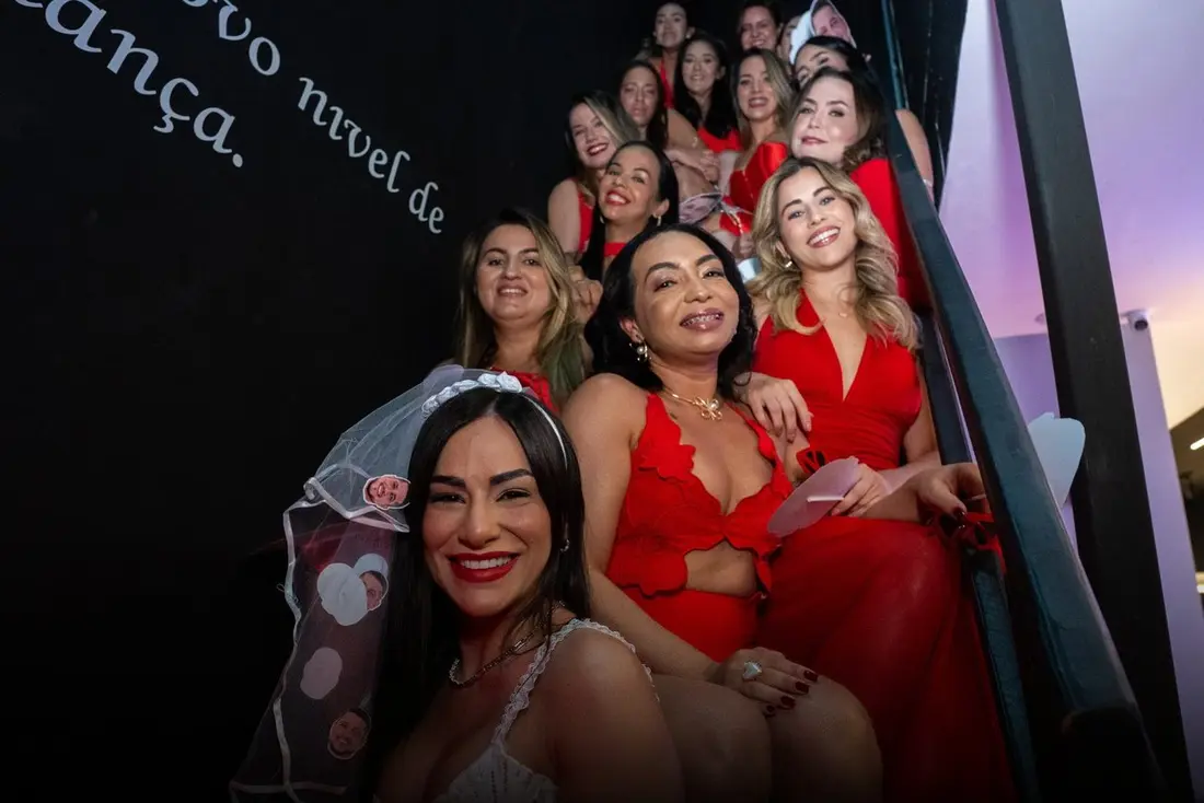 Noiva de véu e amigas de vermelho sentadas na escada
